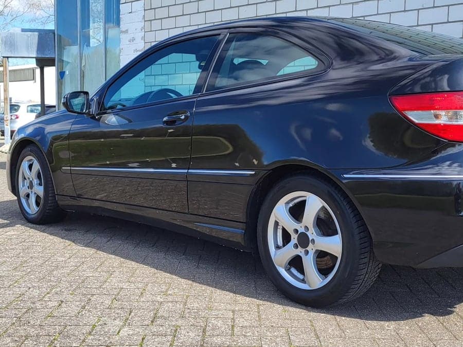 Heckansicht eines schwarzen Mercedes Coupés im Sonnenlicht