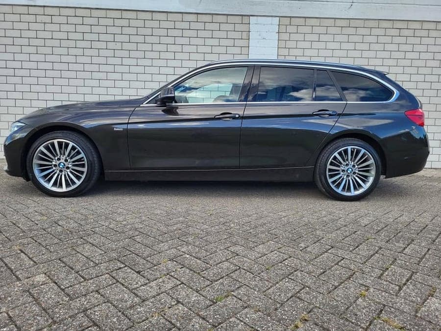 Schwarzer BMW Kombi im Seitenprofil auf gepflastertem Hof